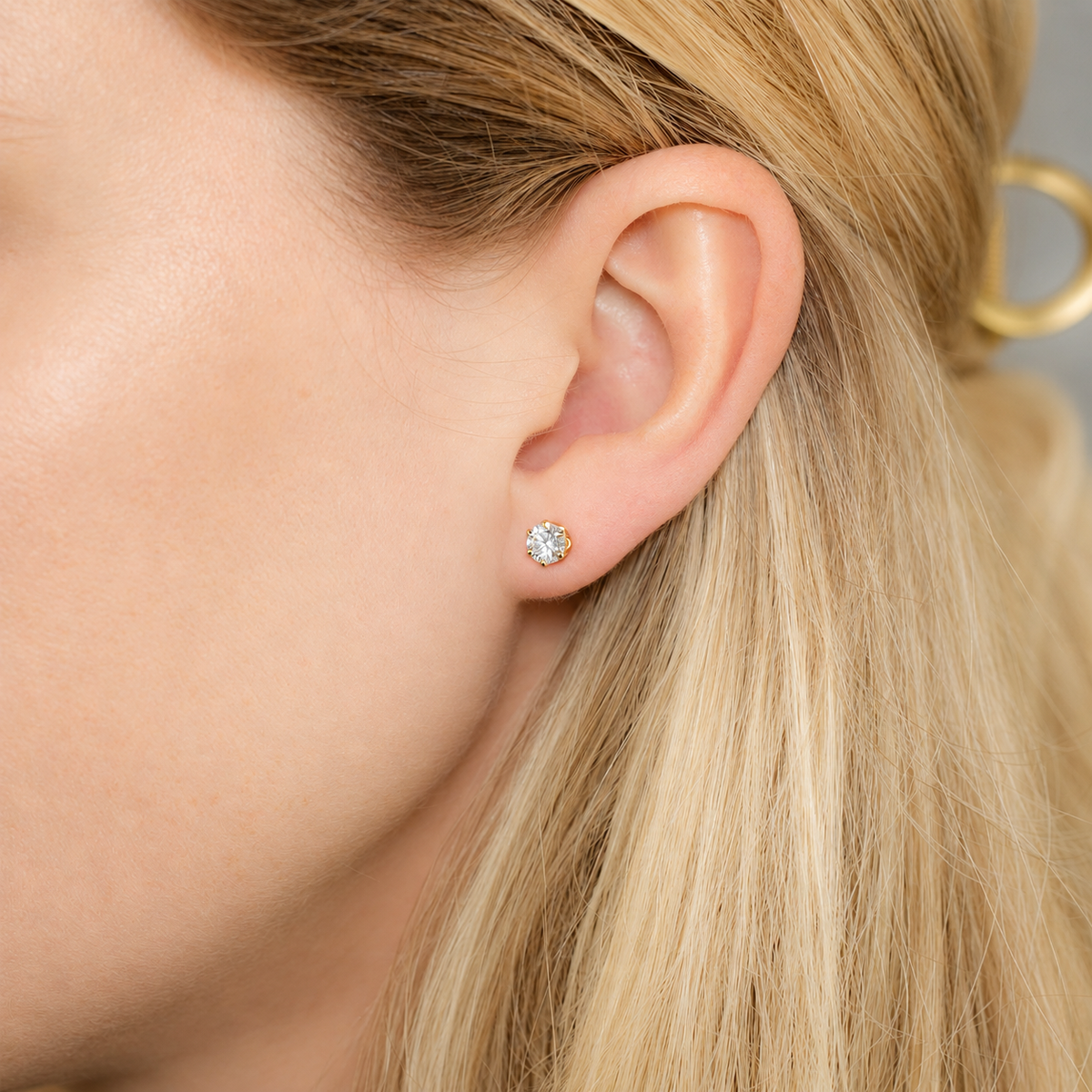 0.50 carat round moissanite stud earring worn on ear in a six-prong 14/20 gold-filled setting.