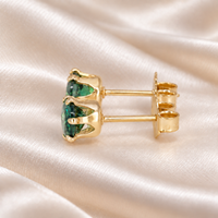 Side profile of a pair of 5mm lab emerald stud earrings showing six-prong gold-filled baskets, straight posts and butterfly backs.